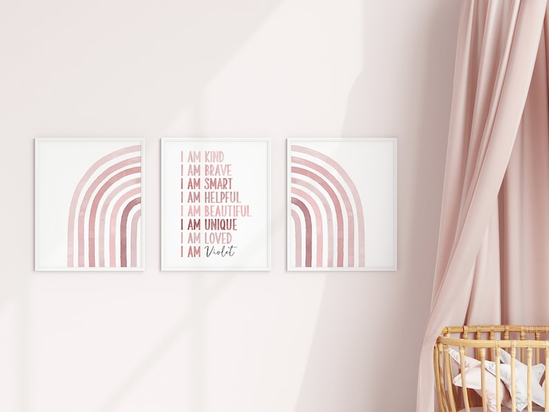 May include: Three framed prints featuring a pink watercolour rainbow design. The centre print includes the text "I am kind, I am brave, I am smart, I am helpful, I am beautiful, I am unique, I am loved, I am Violet".