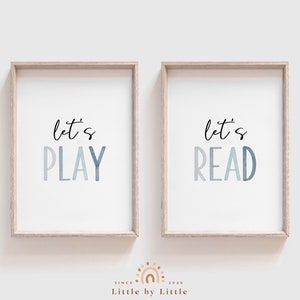 May include: Two framed prints with a white background and blue text. The left print says "let's PLAY" and the right print says "let's READ".