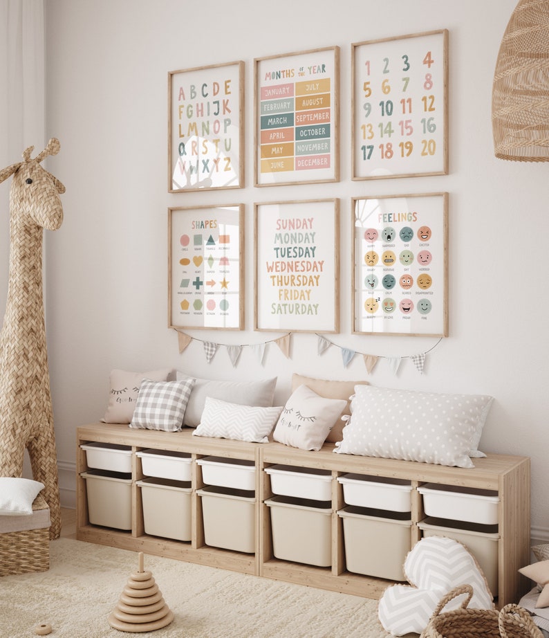 May include: A set of six colorful educational posters for children. The posters feature the alphabet, numbers, months of the year, days of the week, shapes, and feelings. The posters are framed in natural wood and are hung on a white wall.
