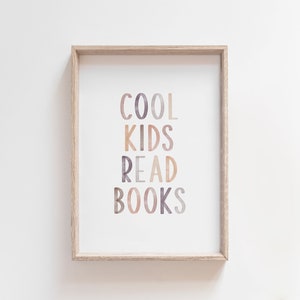 K&ouml;nnte beinhalten: Ein gerahmter Druck mit dem Text "COOL KIDS READ BOOKS" in Aquarell-Stil mit Braunt&ouml;nen, Rosa und Lila.