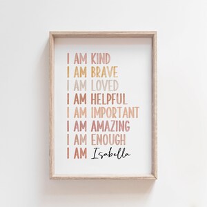 May include: A framed print with a white background and a list of positive affirmations in a rainbow gradient of colors. The text reads "I am kind, I am brave, I am loved, I am helpful, I am important, I am amazing, I am enough, I am Isabella".
