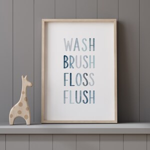 May include: A framed print with the words "WASH BRUSH FLOSS FLUSH" in a blue watercolor design. The print is on a shelf with a wooden giraffe figurine.