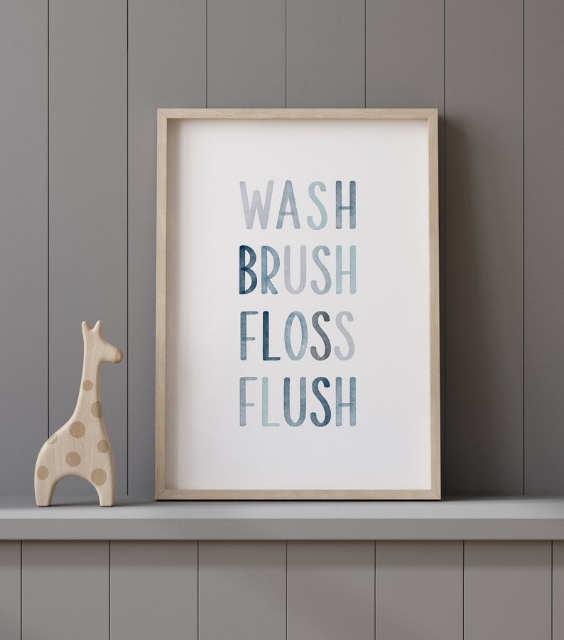 May include: A framed print with the words "WASH BRUSH FLOSS FLUSH" in a blue watercolor design. The print is on a shelf with a wooden giraffe figurine.