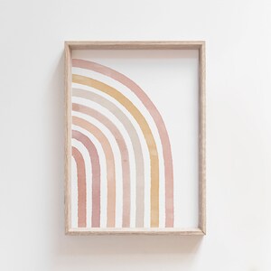 May include: A framed print of a watercolor rainbow in shades of pink, peach, and beige. The rainbow is half a circle and is centered in the frame.