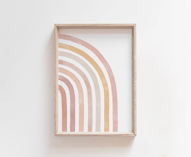 May include: A framed print of a watercolor rainbow in shades of pink, peach, and beige. The rainbow is half a circle and is centered in the frame.