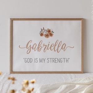 May include: A framed print with a floral design and the name "Gabriella" in cursive script. The text "God is my strength" is printed below the name.