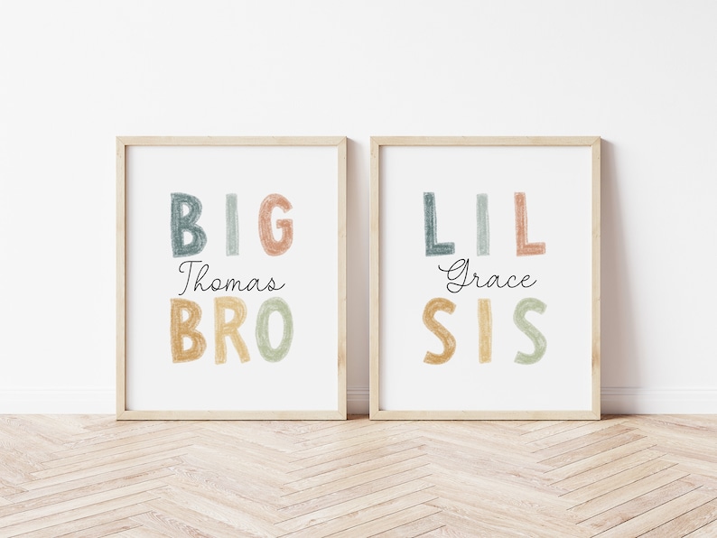 May include: Two framed prints with colorful text. The left print says "BIG Thomas BRO" in a rainbow color scheme. The right print says "LIL Grace SIS" in a rainbow color scheme.