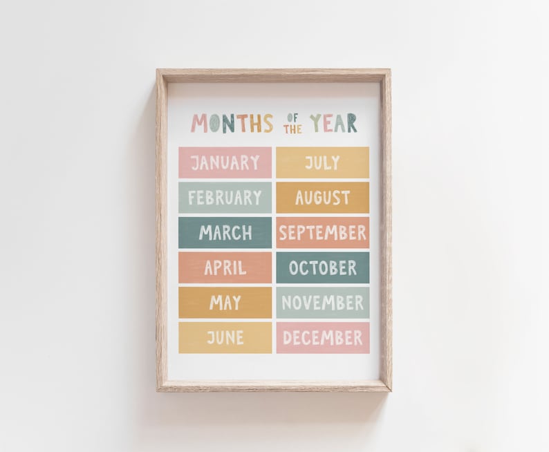May include: A framed printable wall art poster with a colorful design featuring the months of the year in a grid layout. The months are written in a handwritten font and are arranged in two columns. The background is white.