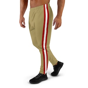 Puede incluir: Pantalones de chándal dorados con rayas rojas y blancas a los lados.