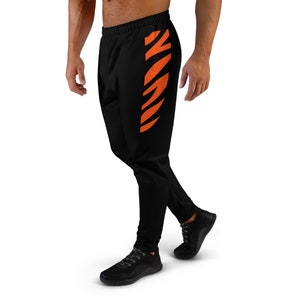 May include: Black sweatpants with an orange stripe down the side of the leg.