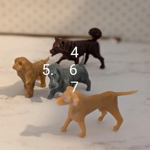 May include: Four plastic toy dogs in different colors and poses. The dogs are numbered 4, 5, 6, and 7.