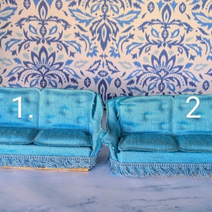 May include: Two miniature blue velvet couches with fringe trim. The couch on the left is labeled "1." and the couch on the right is labeled "2."