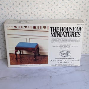 May include: A box for a miniature Chippendale bench, circa 1760. The box shows an image of the assembled bench with a blue upholstered seat and dark wood legs. Text on the box reads "The House of Miniatures" and details about the contents.