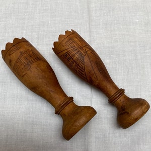 Puede incluir: Dos candelabros de madera con un diseño tallado. Los candelabros son marrones y tienen una parte superior festoneada.