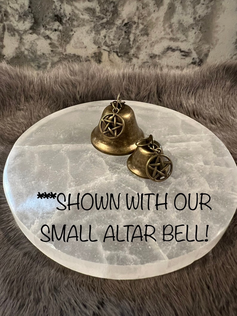 May include: Two gold-toned bells with a pentagram design on a white selenite altar plate. The text "***SHOWN WITH OUR SMALL ALTAR BELL!" is written on the plate.
