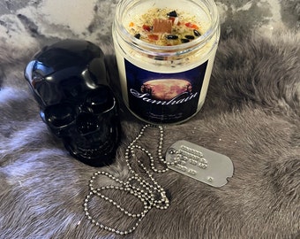May include: A white candle with a black skull, a silver chain, and a silver dog tag. The candle has a label that says "Samhain" and a full moon graphic.