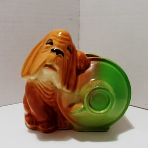 May include: A ceramic planter shaped like a brown basset hound dog with a green planter pot attached to its back.
