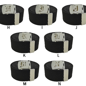 May include: Eight black canvas belts with silver buckles featuring a different letter of the alphabet on each buckle. The letters are in a gothic font.