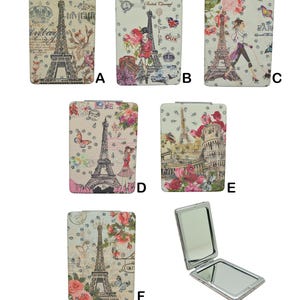 May include: A collection of six rectangular compact mirrors featuring various Paris-themed illustrations, including the Eiffel Tower, floral patterns, and figures, accented with small rhinestones. One mirror is shown open to reveal two reflective surfaces.