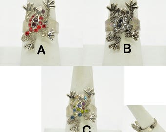 May include: Three silver frog rings with different colored rhinestones. The first ring has red rhinestones, the second ring has clear rhinestones, and the third ring has multi-colored rhinestones.