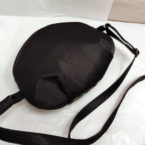 May include: A black crossbody bag with a zipper closure and a long adjustable strap. The bag is made of a smooth, water-resistant fabric.