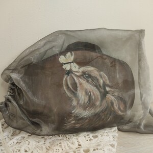 May include: A brown fabric bag with a painted image of a dog looking at a butterfly. The bag is made of a sheer fabric and has a drawstring closure.