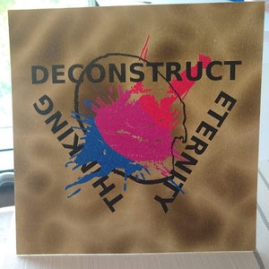 Pode incluir: Um cartão dourado com um círculo preto no centro. O círculo tem um padrão de respingos rosa, vermelho e azul dentro. As palavras "DECONSTRUCT" e "THINKING" estão escritas em preto ao redor do círculo. As palavras "ETERNITY" estão escritas em preto do lado direito do círculo.