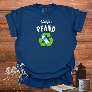 May include: Navy blue t-shirt with the text "Hot for Pfand" above a recycling symbol with a water bottle inside. The shirt is made of a soft material.