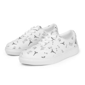 Könnte beinhalten: Weiße Canvas-Sneaker mit niedrigem Schaft und einem schwarz-weißen Druck des Eiffelturms, Weingläsern und anderen Pariser Motiven.