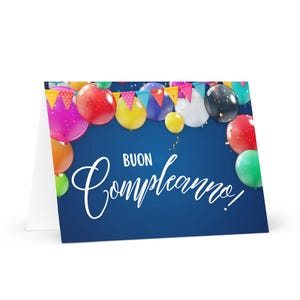May include: A birthday greeting card with a dark blue background and colorful balloons. The card says "Buon Compleanno" in white script. The balloons are red, yellow, green, orange, pink, and black.
