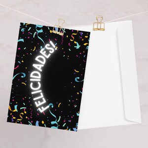May include: A black card with a white design of confetti and the word "FELICIDADES!" in a curved arc.
