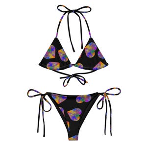 Pode incluir: Um biquíni preto com top triangular e parte de baixo de corte alto. O biquíni é estampado com corações coloridos.