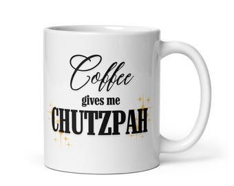 May include: White ceramic coffee mug with the text "Coffee gives me CHUTZPAH" in black script and gold lettering. The mug has a standard handle and a glossy finish. Gold starburst accents are below the word "CHUTZPAH".