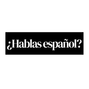 May include: A black rectangular sign with the white text "¿Hablas español?" The text is in a serif font. The question mark is inverted at the beginning of the phrase. The background is white.