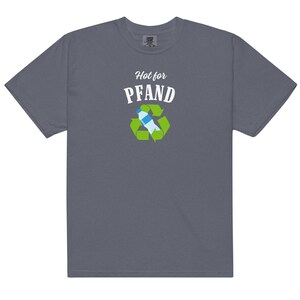 May include: A slate blue t-shirt with the text "Hot for PFAND" above a recycling symbol containing a water bottle. The graphic is in white, green, and blue. The shirt is a short-sleeved, crew neck style.