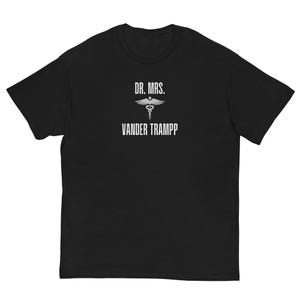 May include: Black t-shirt with white text and a medical symbol. The text reads "DR. MRS. VANDER TRAMPP". The shirt is a short-sleeved, crew neck style.