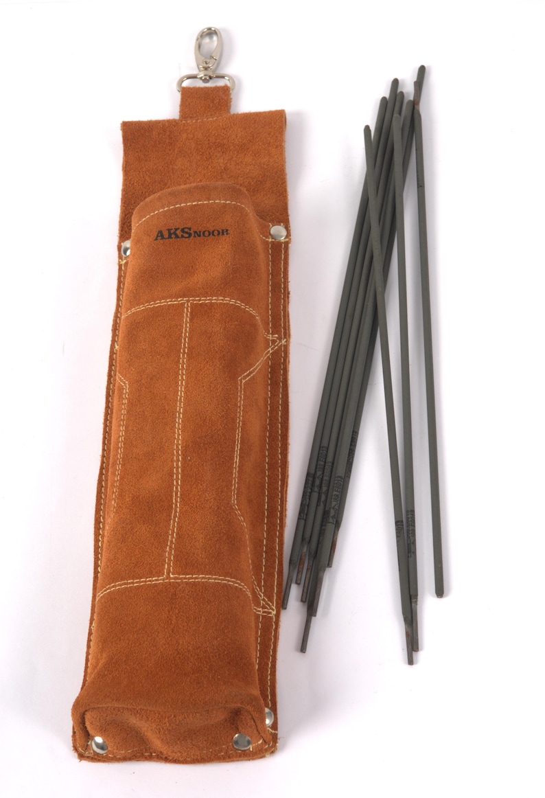 Leather Welding Rod Pouch | Handmade Welder Rod Holder, A brown leather welding rod holder with the text "AKSNOOR" and a set of welding rods. The holder is rectangular with white stitching and a silver clasp. The welding rods are gray and arranged next to the holder.