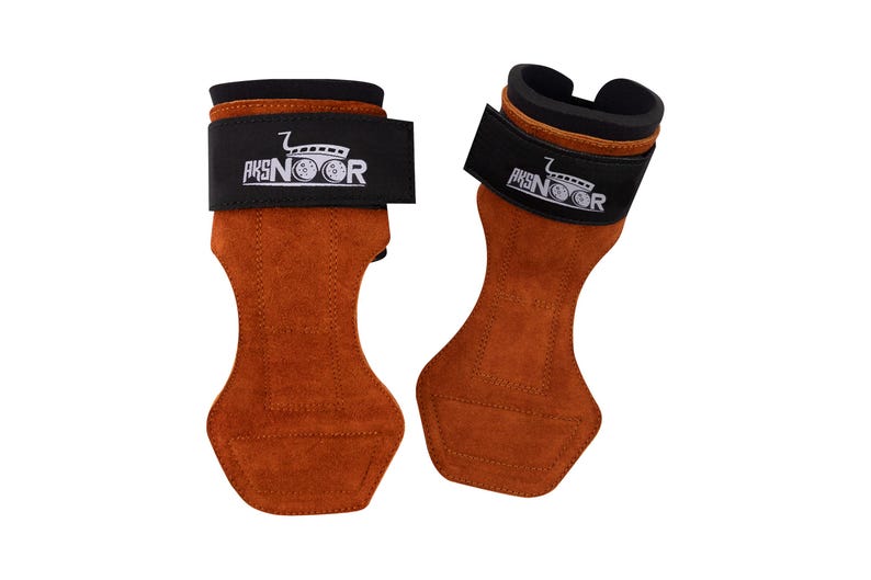 May include: A pair of brown leather weightlifting grips with black wrist straps. The straps feature the text "AKSNOOR" and a logo. The grips are designed to protect hands during workouts and are made of a suede-like material.