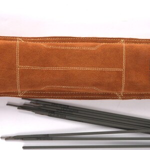 Leather Welding Rod Pouch | Handmade Welder Rod Holder, A brown leather welding rod holder with the text "AKS Noor" and several welding rods. The holder has a rectangular design with white stitching and metal rivets. The welding rods are dark gray.