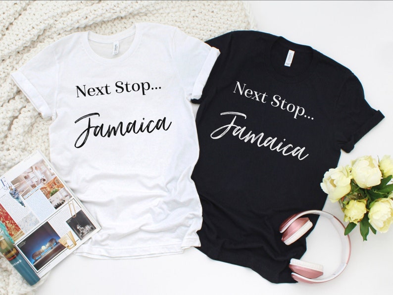 May include: Two t-shirts, one white and one black, with the text "Next Stop... Jamaica" in a cursive font.