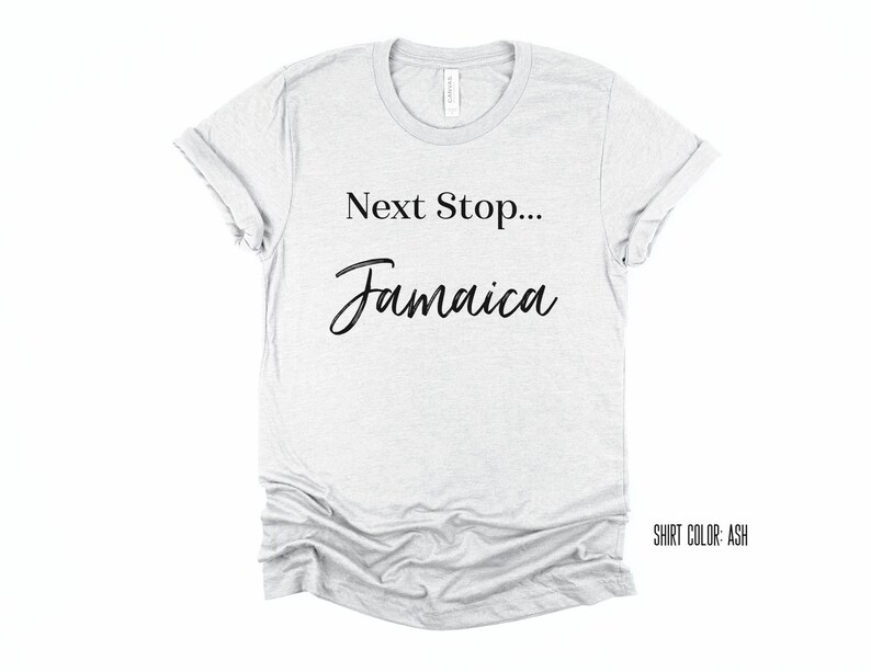 May include: A light grey t-shirt with the text "Next Stop... Jamaica" in black lettering. The shirt colour is ash.