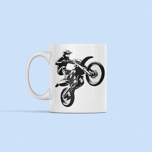 May include: White ceramic mug with a black silhouette of a motocross rider performing a wheelie on a dirt bike.