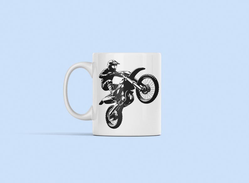 May include: White ceramic mug with a black silhouette of a motocross rider performing a wheelie on a dirt bike.