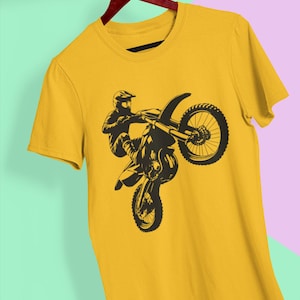May include: A yellow t-shirt with a black silhouette of a motocross rider performing a wheelie.