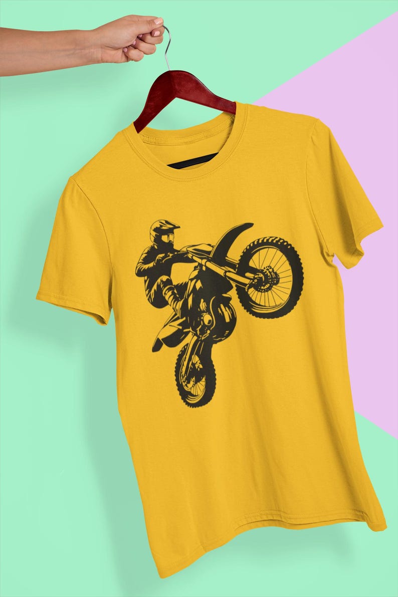 May include: A yellow t-shirt with a black silhouette of a motocross rider performing a wheelie.
