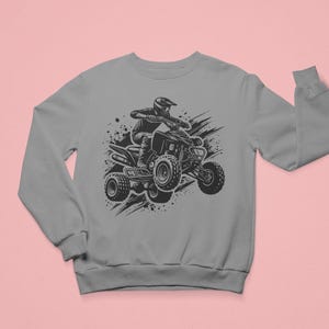 May include: A gray sweatshirt with a black and white illustration of a person riding an ATV. The ATV is surrounded by black splatters of paint.