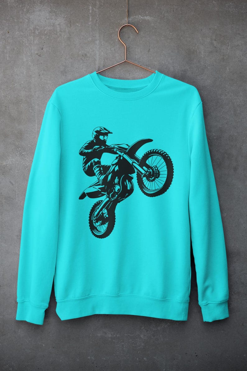 May include: A turquoise blue sweatshirt with a black silhouette of a motocross rider performing a wheelie on their dirt bike.