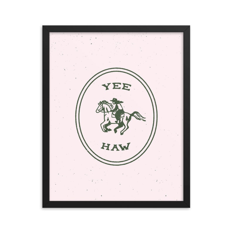 May include: A framed print with a pink background and a green circle containing a cowboy riding a horse. The circle has the text "YEE HAW" inside.