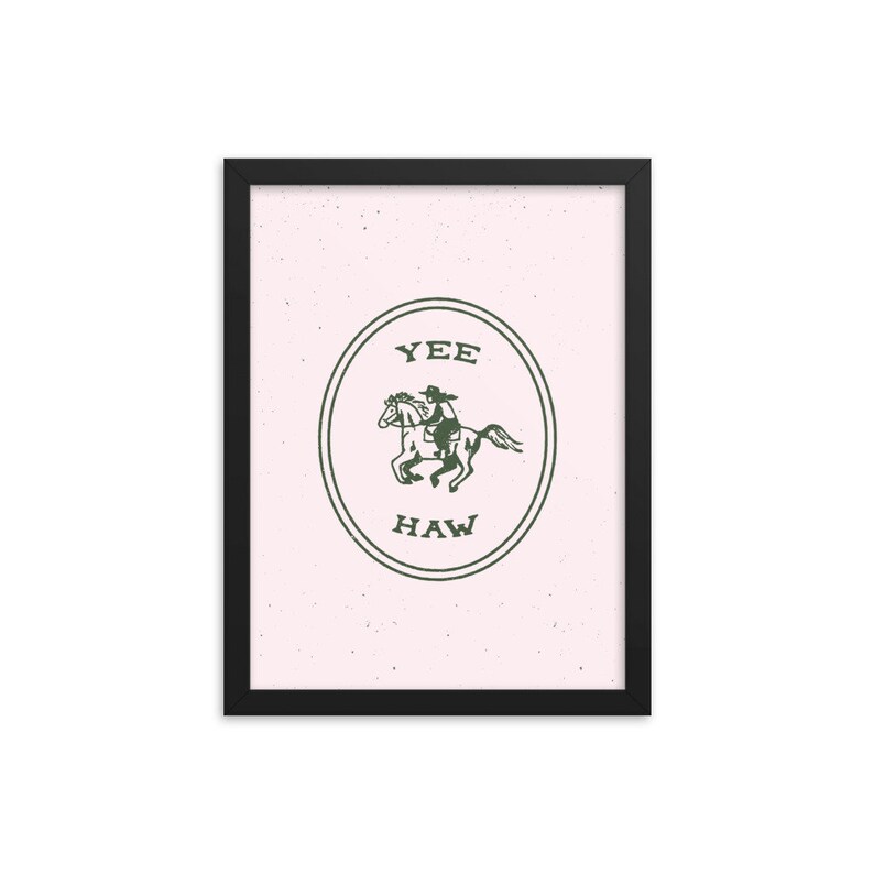 May include: A framed print with a pink background and a green circle containing a cowboy riding a horse. The circle has the text "YEE HAW" inside.