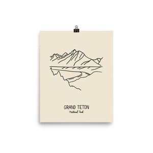 May include: Line art illustration of the Grand Teton mountain range with a river flowing through the valley. The text "Grand Teton National Park" is below the image.